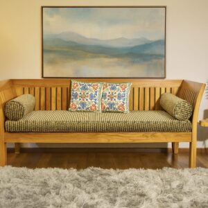 Teak day bed with colorful cushion in a cozy living room .