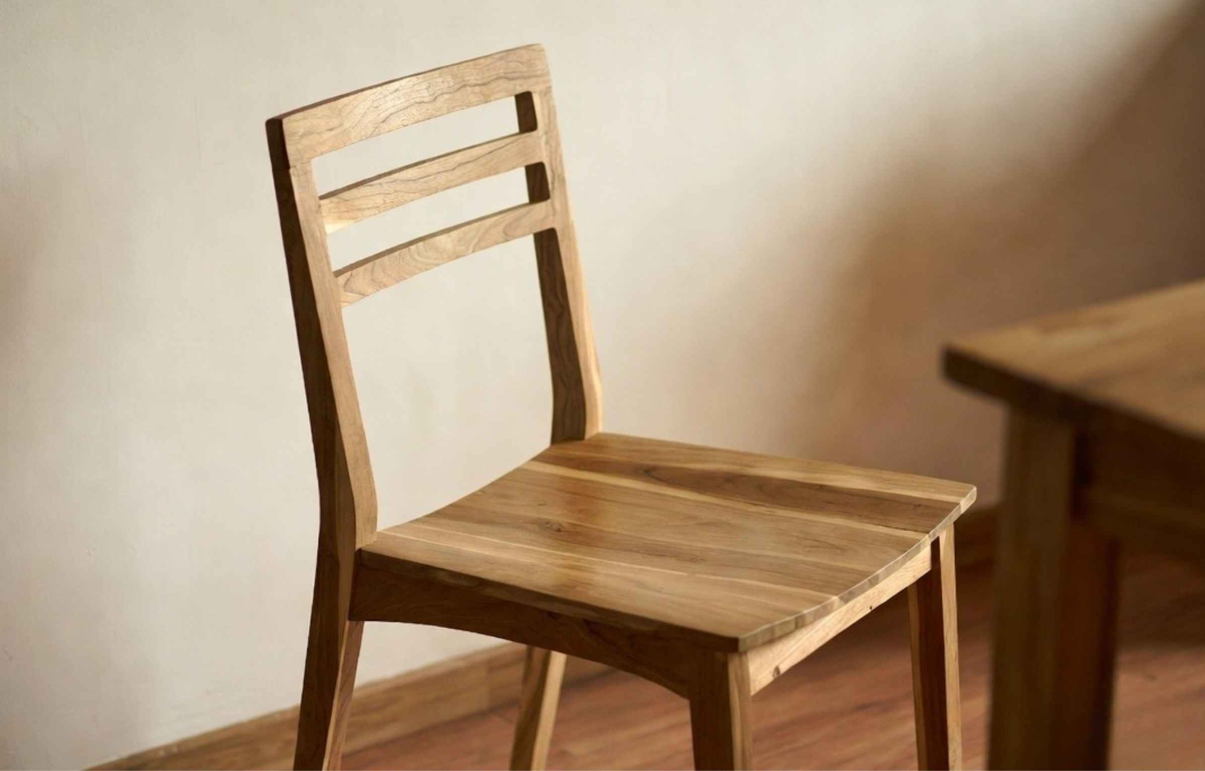 Solid teak dining chair with natural grain detail positioned next to a wooden dining table, showing how to choose dining chairs.