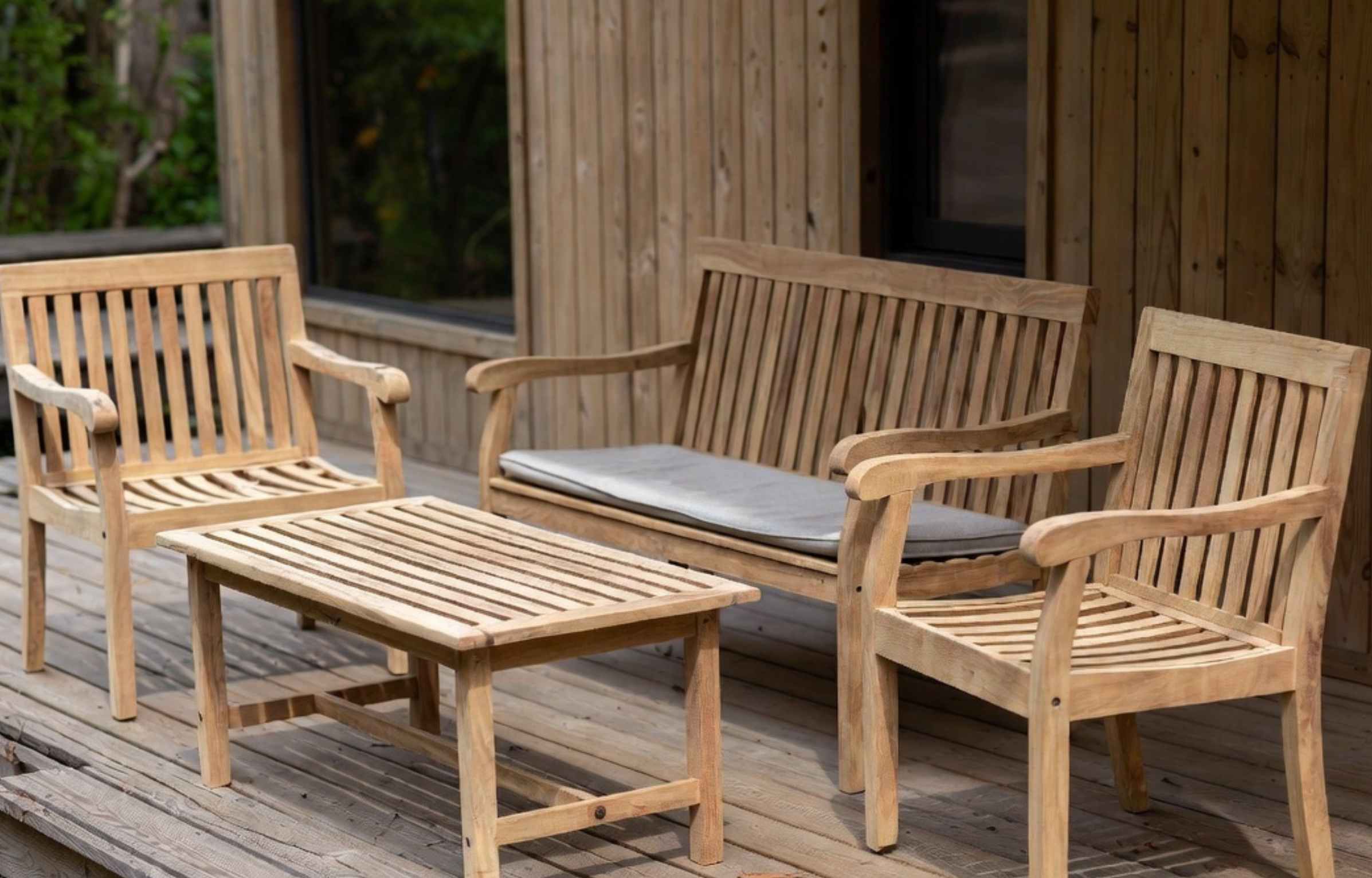 Outdoor teak furniture Malaysia wooden patio set with chairs, bench, and table on a deck.
