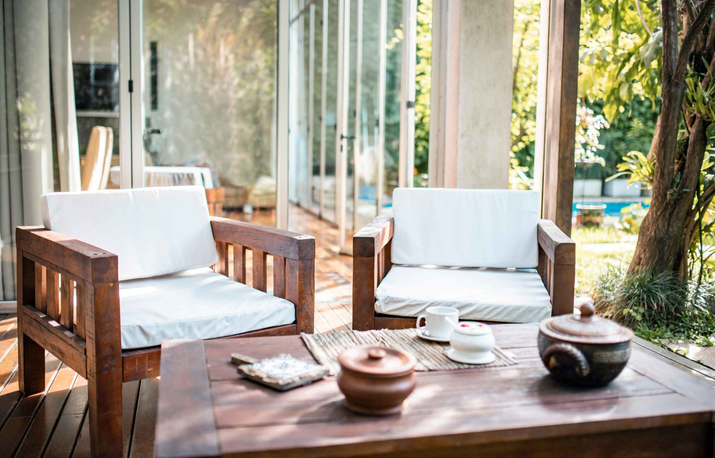 Outdoor teak furniture Malaysia lounge chairs with cushions and table in a bright garden setting.