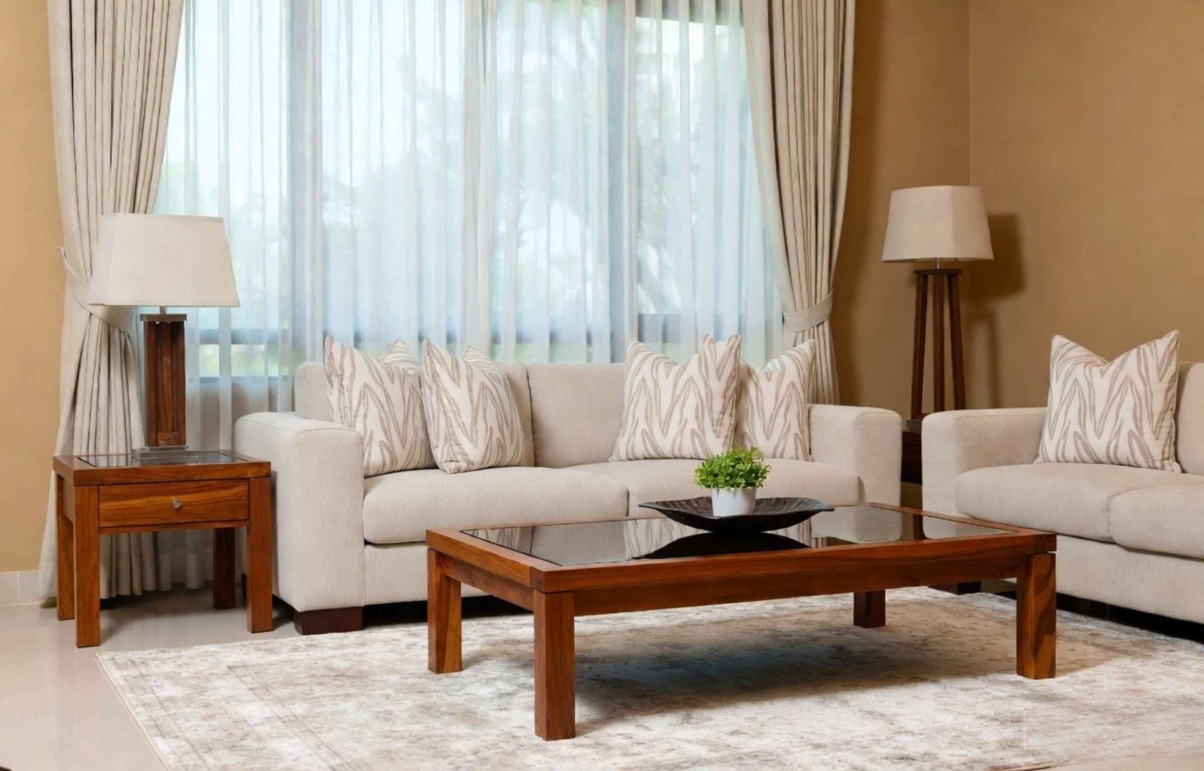 Teak coffee table with sofa set and cushions in a bright living room with curtains and lamps.